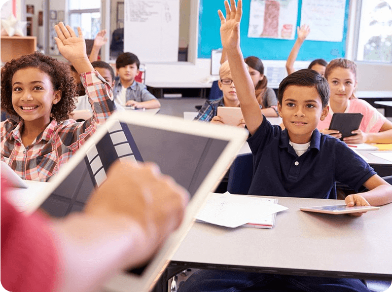 A group of students in class with one holding up their hands.